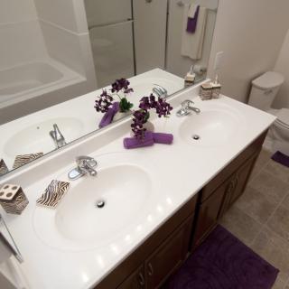 A modern bathroom with a double sink, decorated with flowers and purple accents.