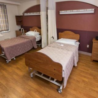 A hospital room with two patient beds and wooden furnishings.