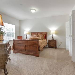 A cozy, traditionally decorated bedroom featuring a wooden bed, matching nightstands, and soft lighting.