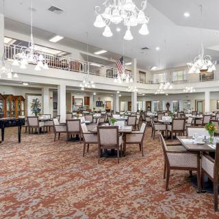 A spacious and elegantly designed dining area with multiple tables and chandeliers.