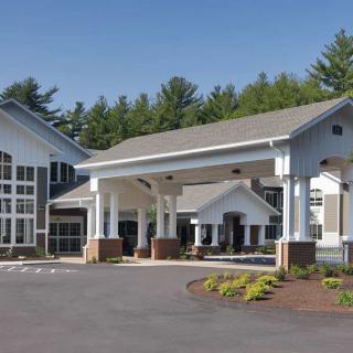 Main entrance of a modern building with covered driveway and landscaped surroundings.