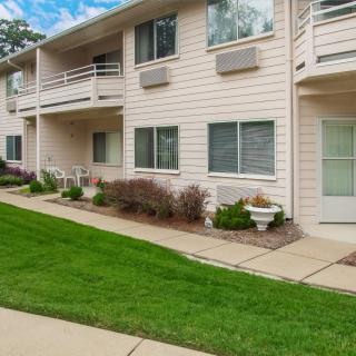Exterior view of a residential apartment building with balconies and a well-maintained lawn.