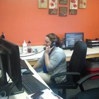A woman working at her desk, talking on the phone in an office setting.