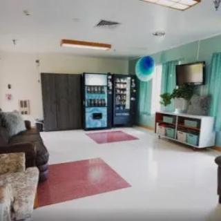 A lounge area featuring vending machines, seating, and a television.