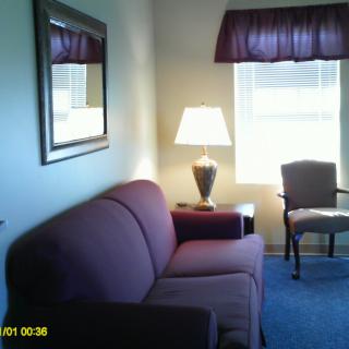 A cozy living room with a sofa, chair, and lamp by the window.