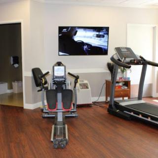 A well-equipped fitness room featuring a treadmill and a stationary bike, with a television mounted on the wall.
