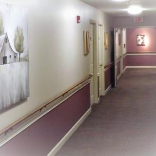 A well-lit hallway with paintings on the walls.