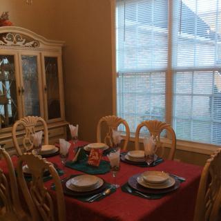 A dining room with a table set for six, featuring a china cabinet and large window.
