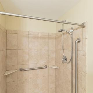 A tiled shower equipped with a showerhead and safety grab bars.