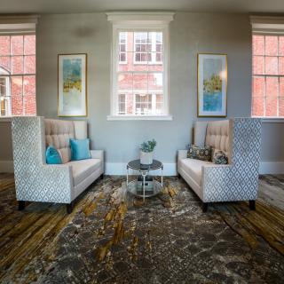 A cozy living room with two patterned armchairs, colorful pillows, and modern artwork.