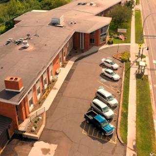Aerial view of a building with a parking lot featuring several vehicles.