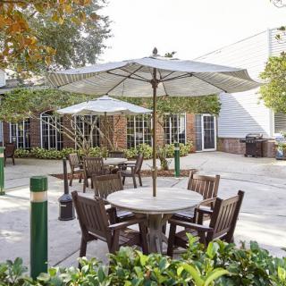 A peaceful outdoor patio area with tables, chairs, and umbrellas surrounded by greenery.