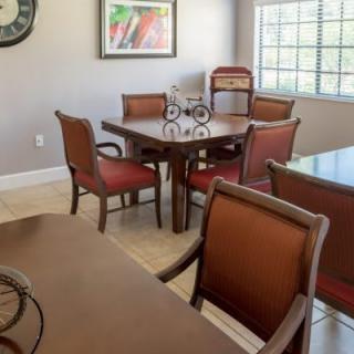 A dining room with a wooden table, upholstered chairs, and artwork on the wall.