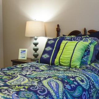 A cozy bedroom setup with a lamp and colorful bedding.