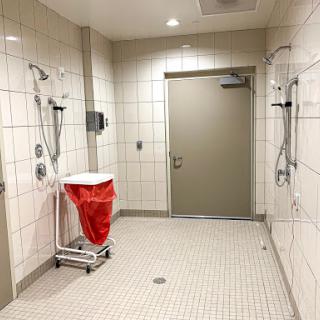 A spacious and modern bathroom featuring shower facilities and a waste disposal bin.