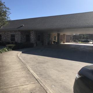 A driveway leading to the entrance of a building with a canopy.