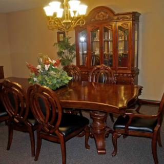 A beautifully arranged dining room featuring an elegant wooden table and chairs, complemented by a stylish chandelier and a display cabinet.
