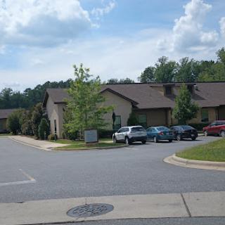 A view of a residential area featuring multiple buildings and parked cars under a partly cloudy sky.
