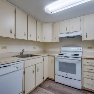 A cozy kitchen with cream-colored cabinets, an electric stove, and a dishwasher.