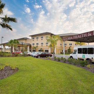 A healthcare facility with well-maintained landscaping and a shuttle bus in front.