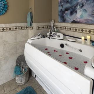 A cozy bathroom with a bathtub filled with water and rose petals, flanked by candles and decorative elements.
