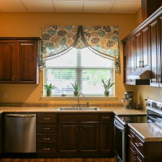 A beautifully designed kitchen featuring dark wood cabinets, modern appliances, and a cozy window area with floral curtains.