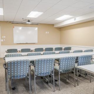 A spacious and organized meeting room equipped with chairs and tables, ready for a conference or group discussion.