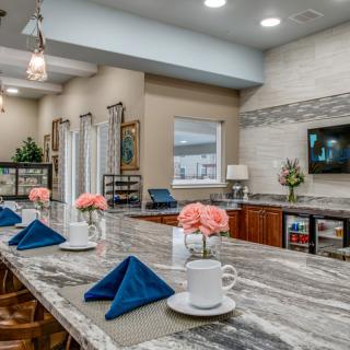 A modern kitchen with a marble countertop set for dining, featuring elegant decor and fresh flowers.