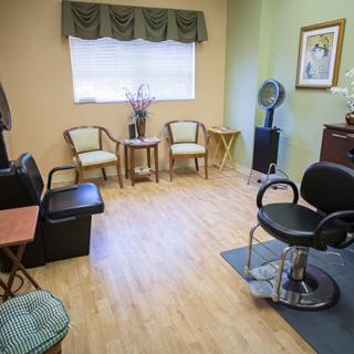 A cozy salon room featuring a waiting area with chairs and a styling station.