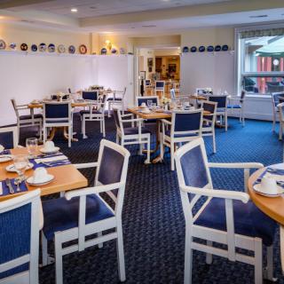 A neatly arranged dining area with tables and chairs, ready for guests.