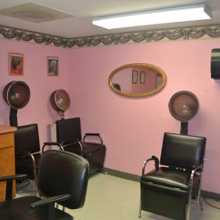 A cozy hair salon featuring pink walls, styling chairs, and hair dryers.