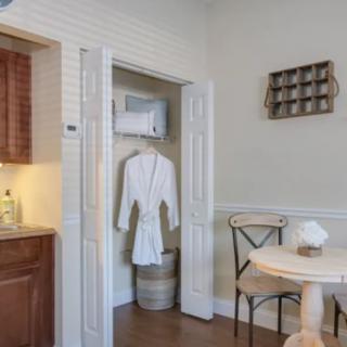 A cozy interior featuring a kitchenette, a small table with chairs, and a bathrobe hanging in an open closet.