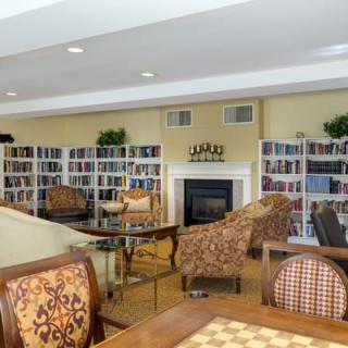 A cozy library space with armchairs, bookshelves, and a fireplace.