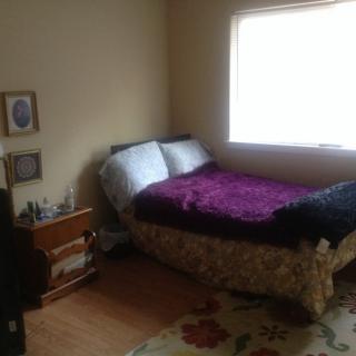 A cozy bedroom with a bed, nightstand, and window.