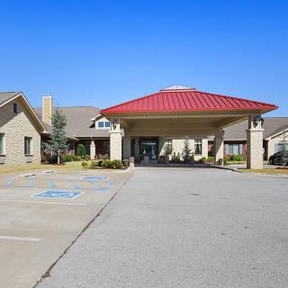 A building entrance with a red roof and an adjacent parking lot under a clear blue sky.