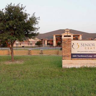 A senior living facility with a sign and surrounding greenery.