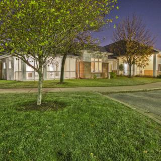 A suburban house at night with a well-maintained lawn and trees.