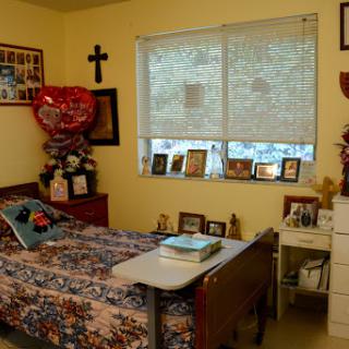 A cozy bedroom featuring a neatly made bed, personal photographs on display, and warm decor.