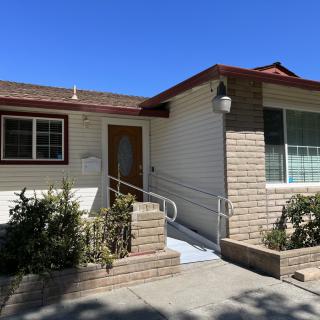 A suburban house with a front entrance ramp and brick facade under a clear blue sky.