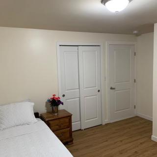 A minimalist bedroom with a bed, nightstand, and wooden flooring.