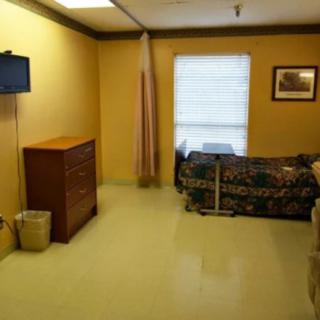 A simple hospital room with a bed, television, and basic furnishings.