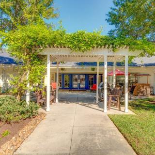 A welcoming entrance featuring a pergola-covered pathway surrounded by lush greenery and landscaping.