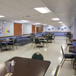 An empty cafeteria with neatly arranged tables and chairs.