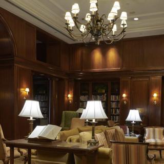 A cozy reading room with elegant wood paneling and a chandelier.