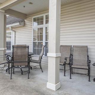 A cozy covered patio with a set of chairs and a table.