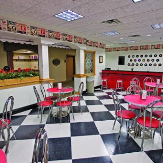 An inviting diner interior featuring checkered flooring and vibrant red accents.
