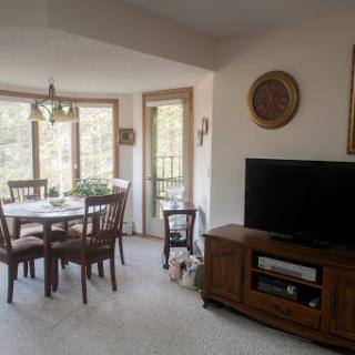 A cozy dining area connected to a living space, filled with natural light and wooden furnishings.