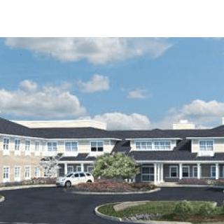 A large building with a parking lot under a partly cloudy sky.