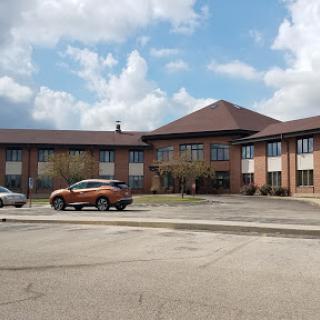A serene view of a multi-story brick building under a partly cloudy sky.