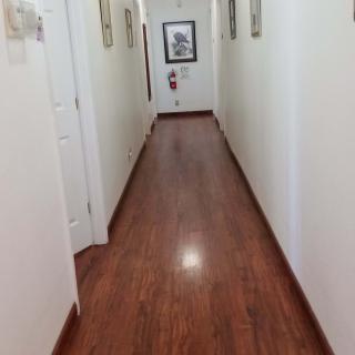 A long hallway with wooden flooring and paintings on the walls.